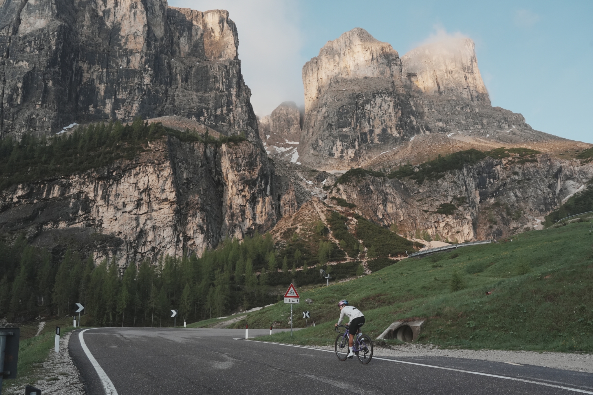 Solo cyclist riding beneath the Dolomites rock towers