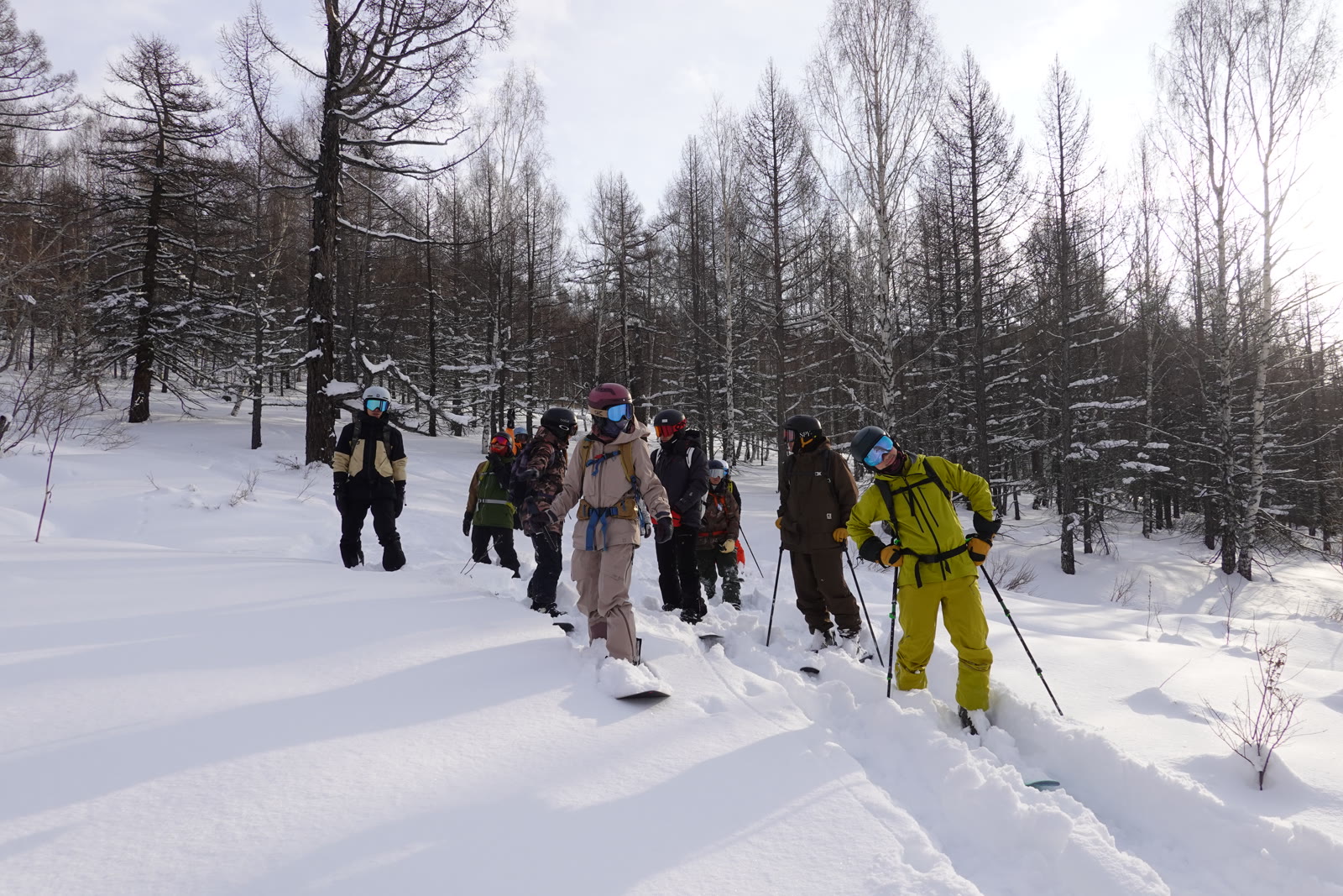 A group in colourful ski gear making their way through fresh snow together