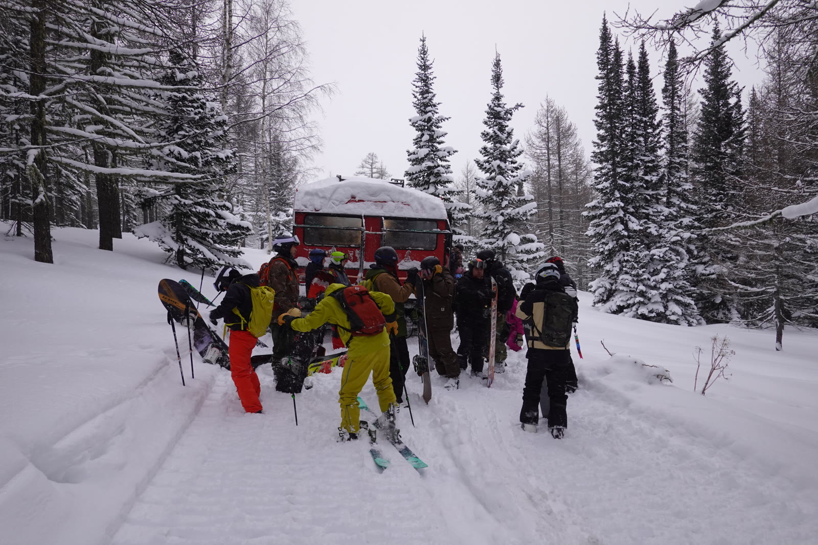 Skiers gathering beside a red snowcat for their next run